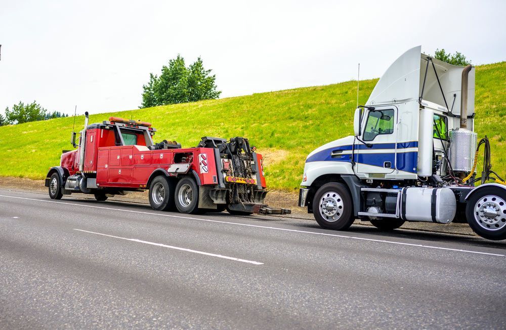 A Tow Truck Is Towing A Semi Truck On The Side Of The Road — Gympie/Childers Towing Pty Ltd in Sunshine Coast, QLD