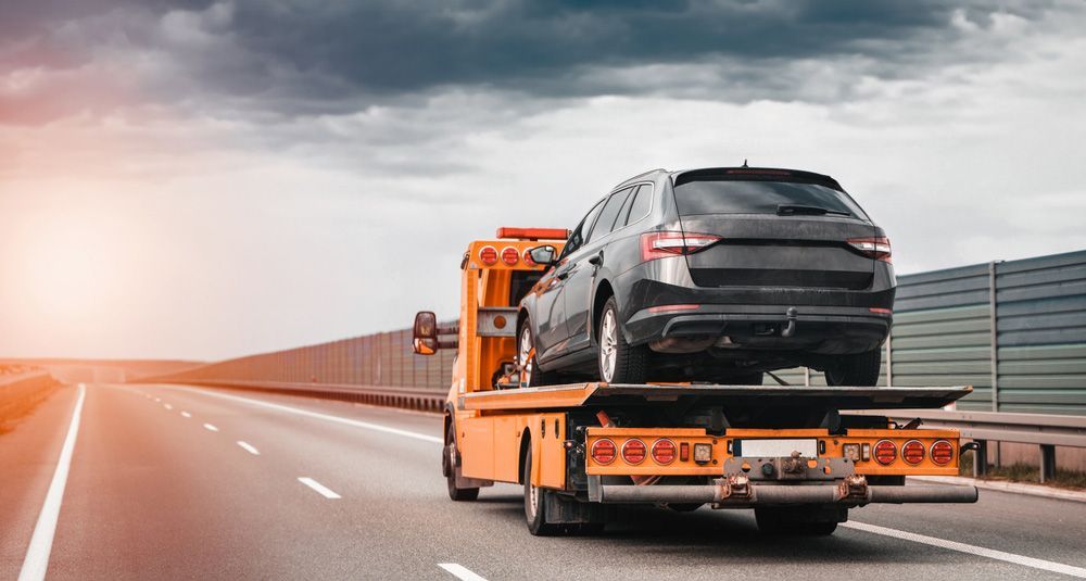 A Tow Truck Is Towing A Car On A Highway — Gympie/Childers Towing Pty Ltd in Sunshine Coast, QLD