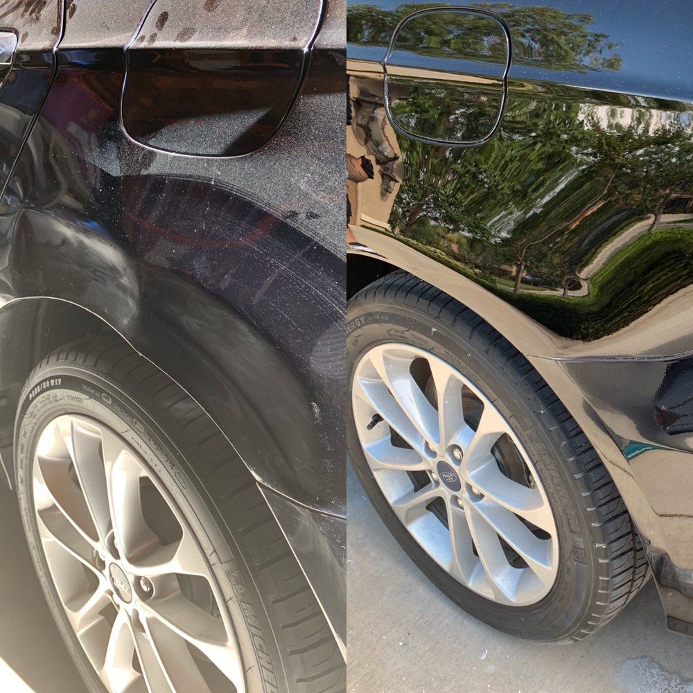 Close-up of two parked cars, showing silver wheels and a black car’s glossy side reflecting trees.