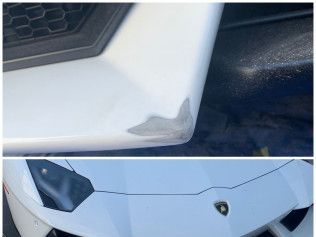 Close-up of a white sports car’s front bumper with scuff damage near the wheel arch