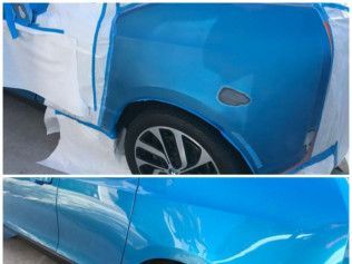Blue car door panel in a workshop, partially masked with tape and paper for paint repair