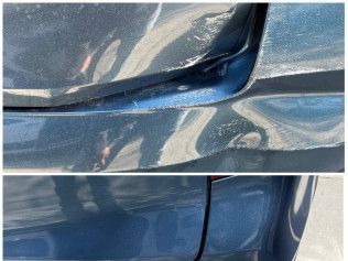 Close-up of a blue car door with a deep dent and creased metal near the panel seam