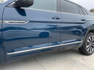 Blue SUV side view with chrome trim parked on a concrete driveway