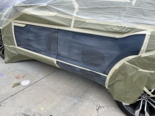 Car covered with plastic and masking tape, parked on a concrete driveway