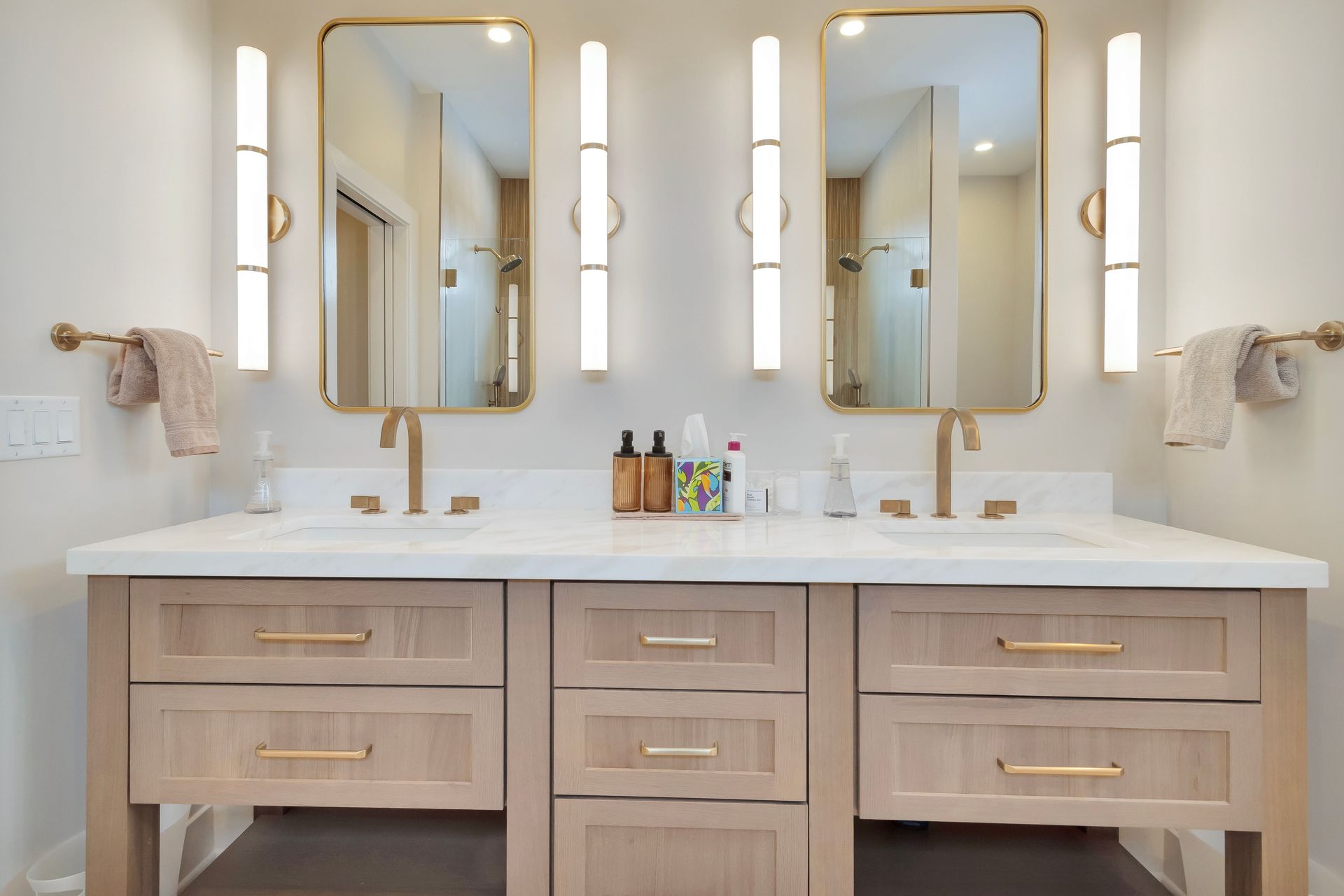 Double vanity bathroom with mirrors, sconces, and wooden cabinets.