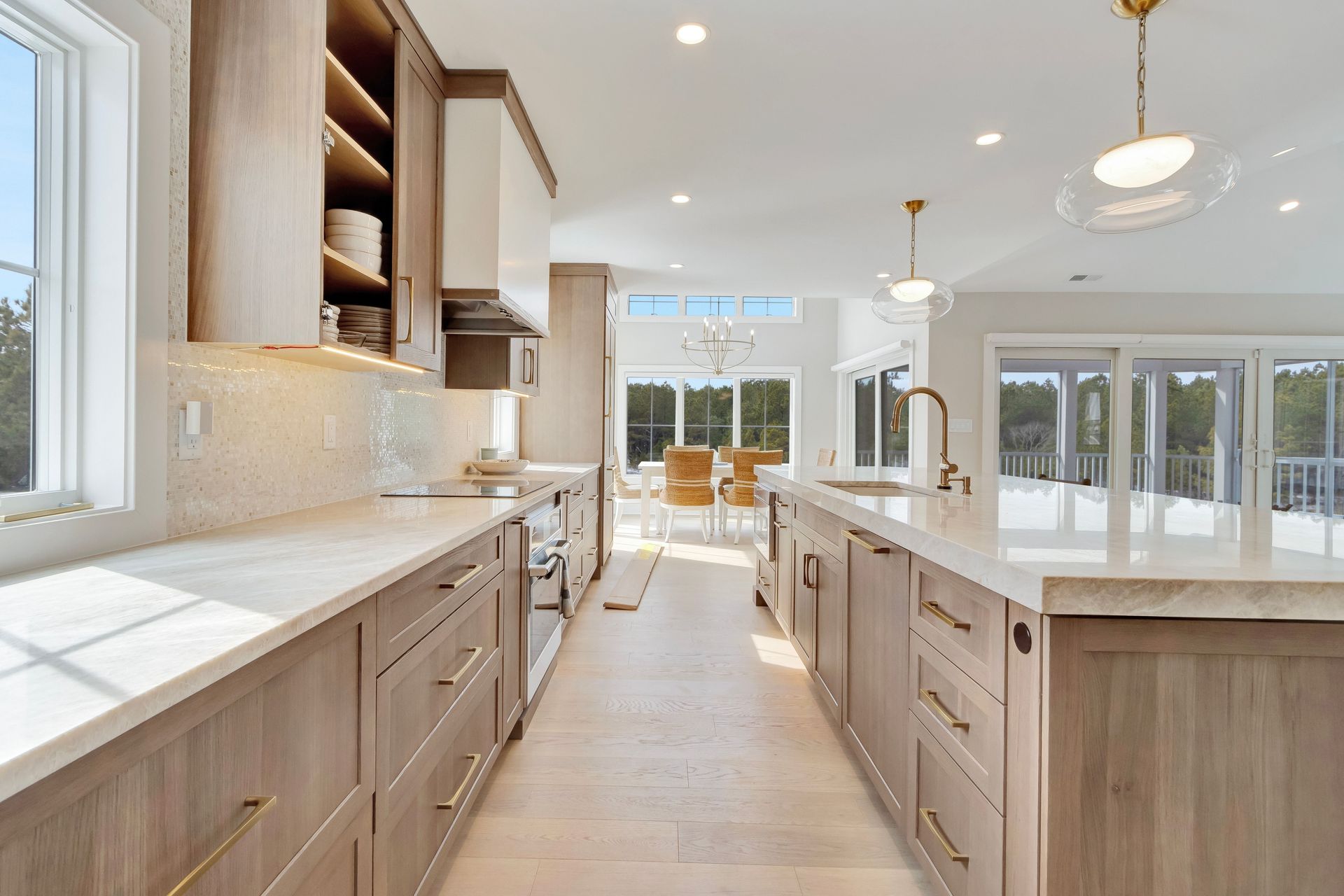 Modern kitchen with light wood cabinets, white countertops, and open to a dining area.