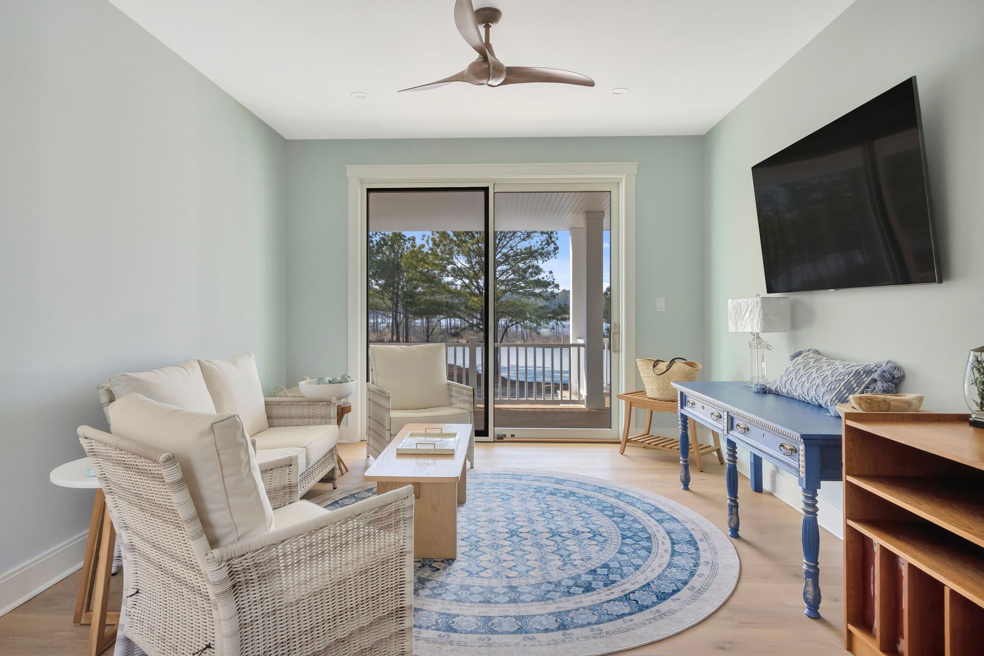 Living room with wicker furniture, a blue rug, and a sliding glass door to a balcony.
