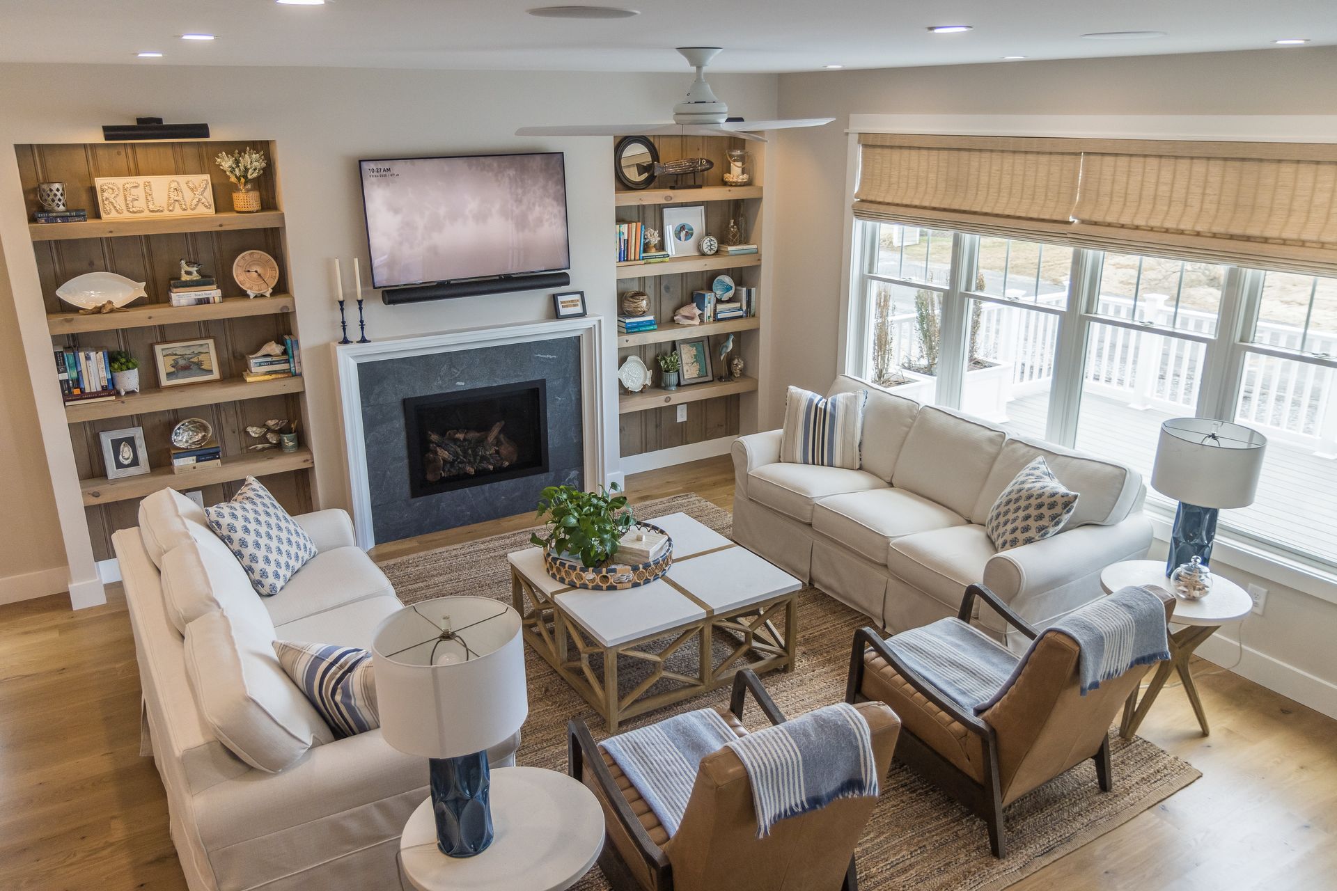 Living room with built-in bookshelves, fireplace, light-colored sofas, and a woven coffee table.