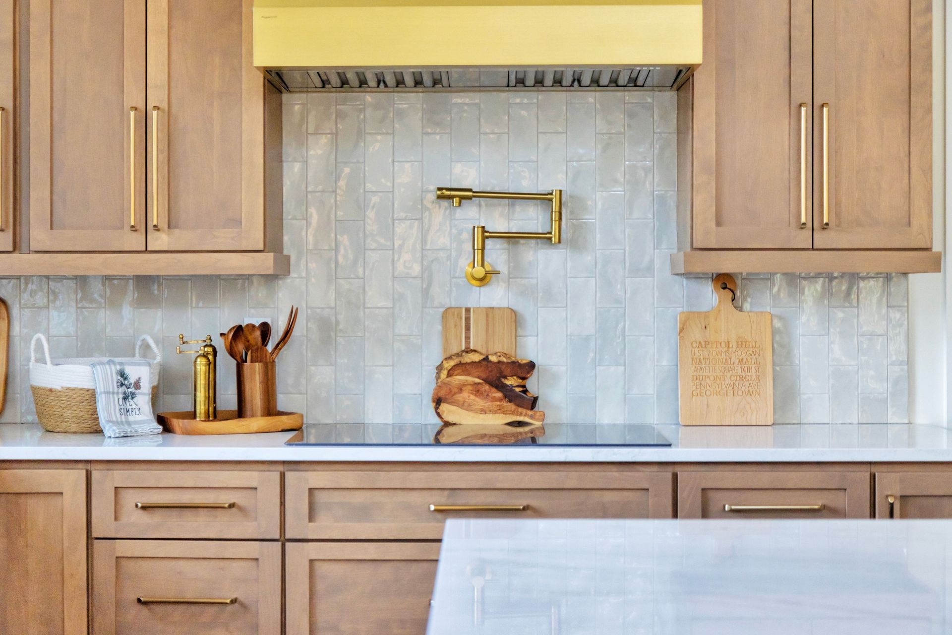 Modern kitchen with tan cabinets, gold accents, and white backsplash.