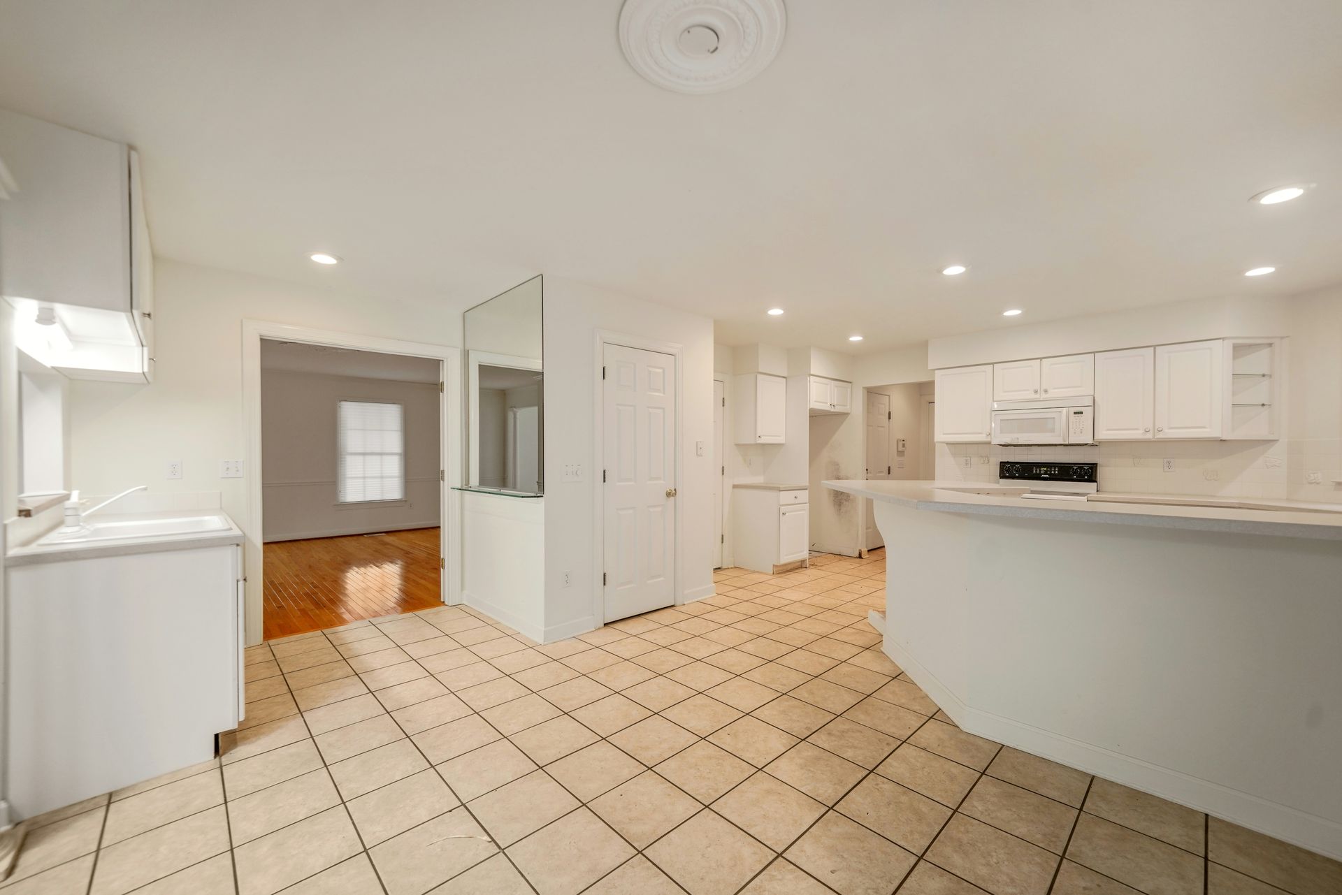 White kitchen with tile floor, cabinets, and a curved countertop.