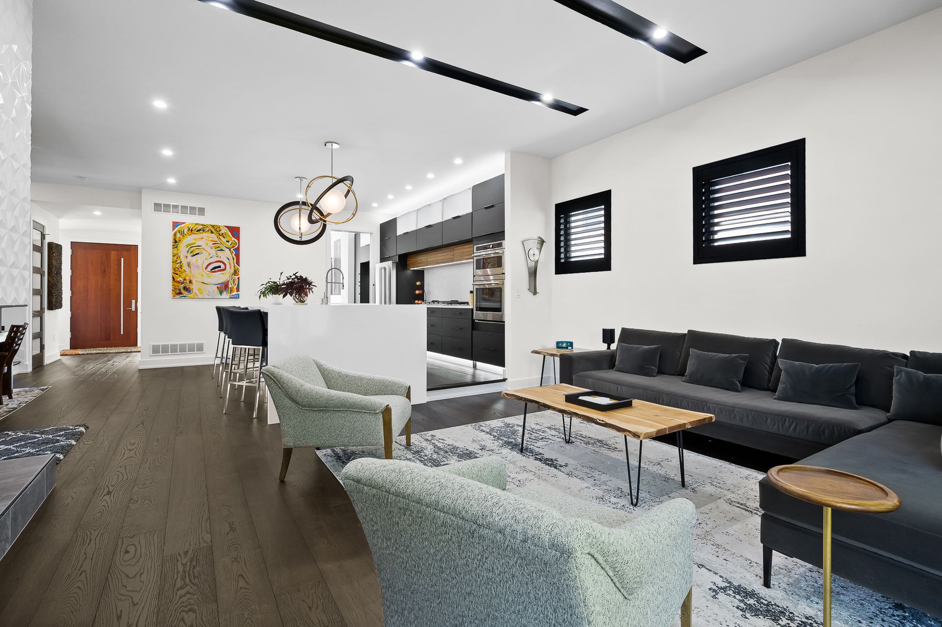 Modern living room with dark wood floors, white walls, and gray furniture.