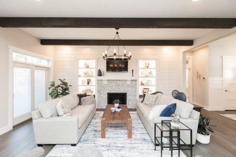 Living room with gray couches, fireplace, and dark wood beams on the ceiling.