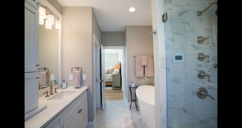 Bathroom with vanity, freestanding tub, and shower, in neutral tones.
