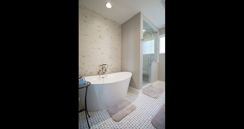 White, modern bathroom with a tub, shower, and patterned floor.