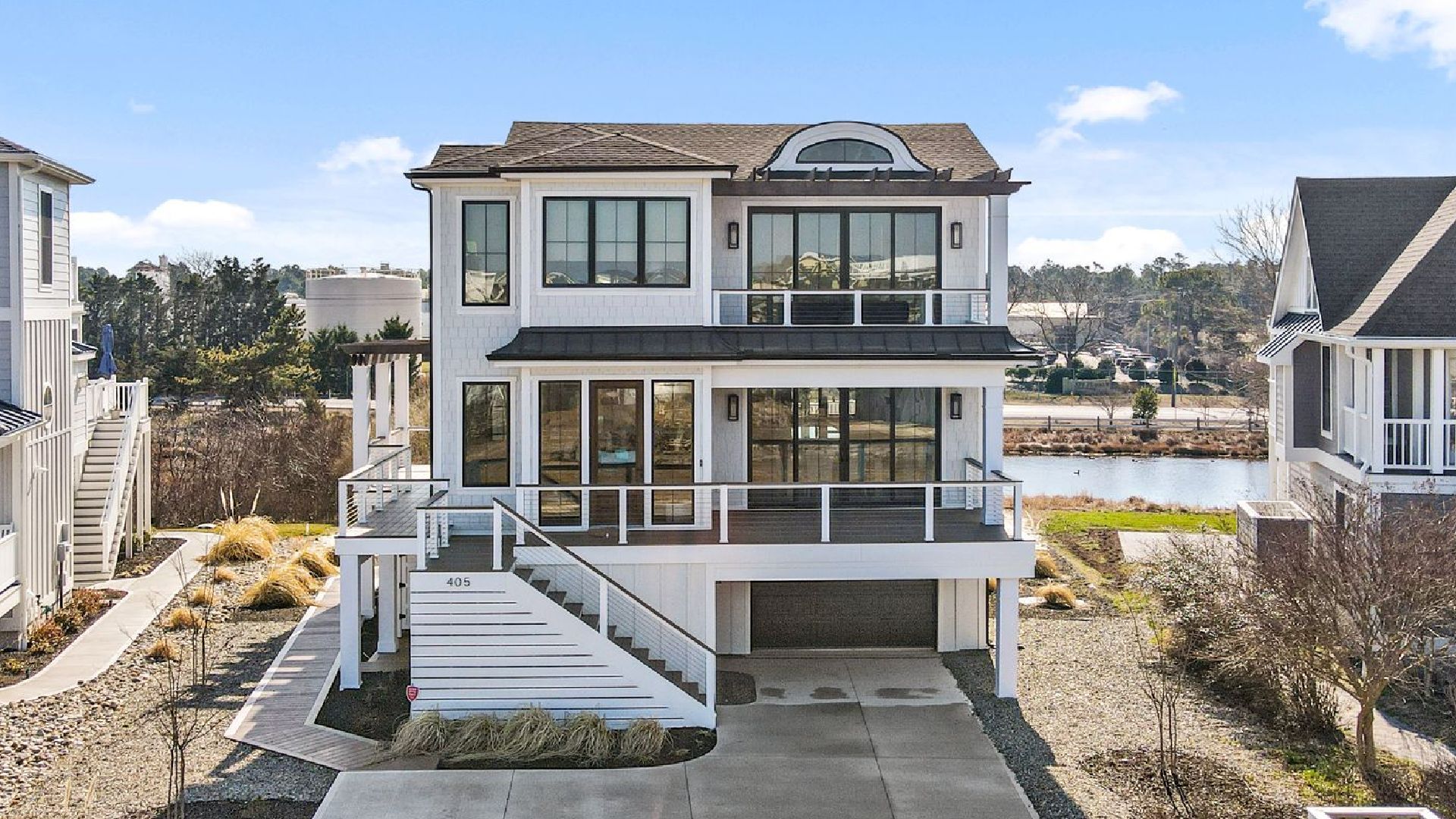 Three-story white house with black trim and large windows, overlooking a waterfront.