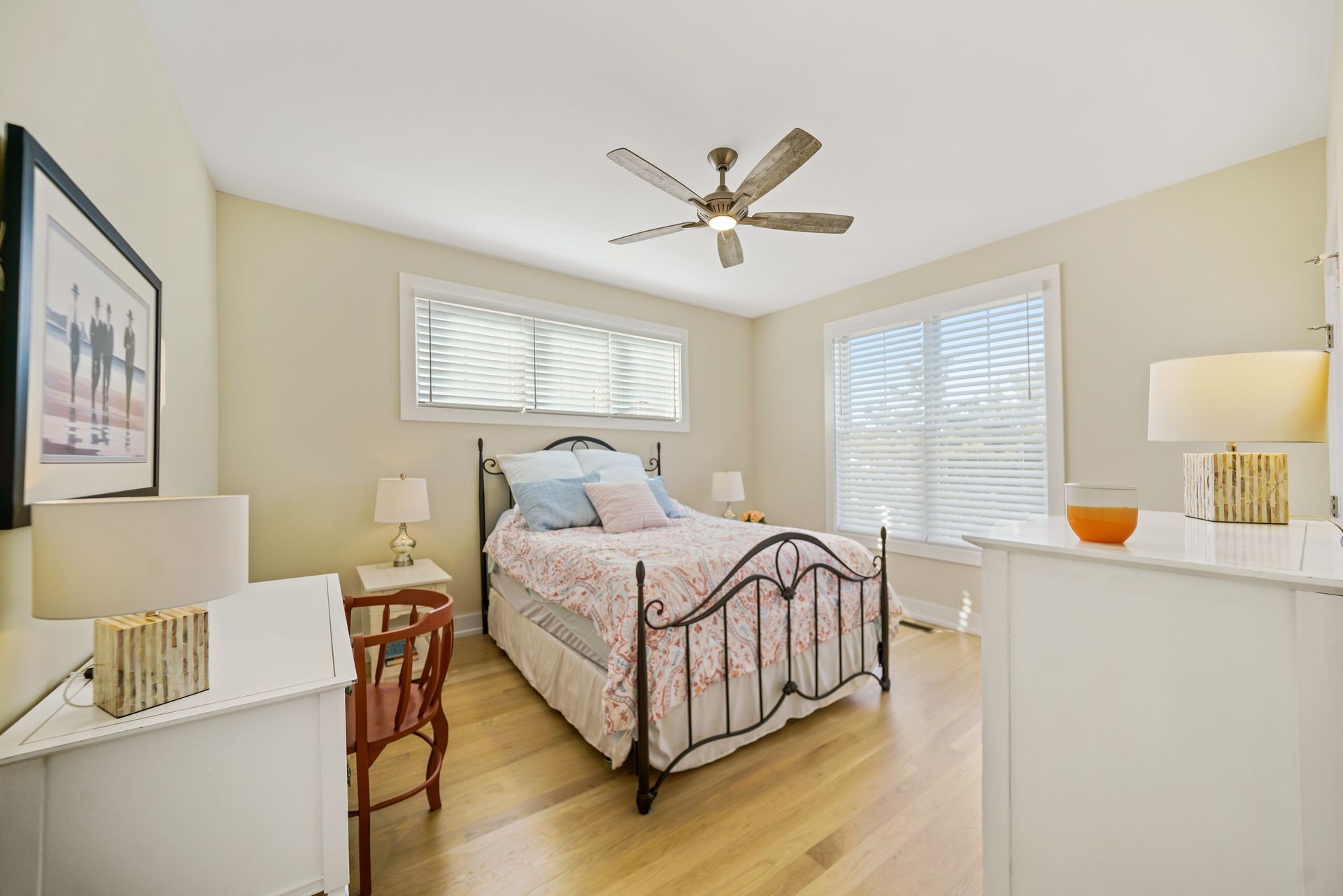 Bright bedroom with a single bed, white dressers, ceiling fan, and hardwood floor