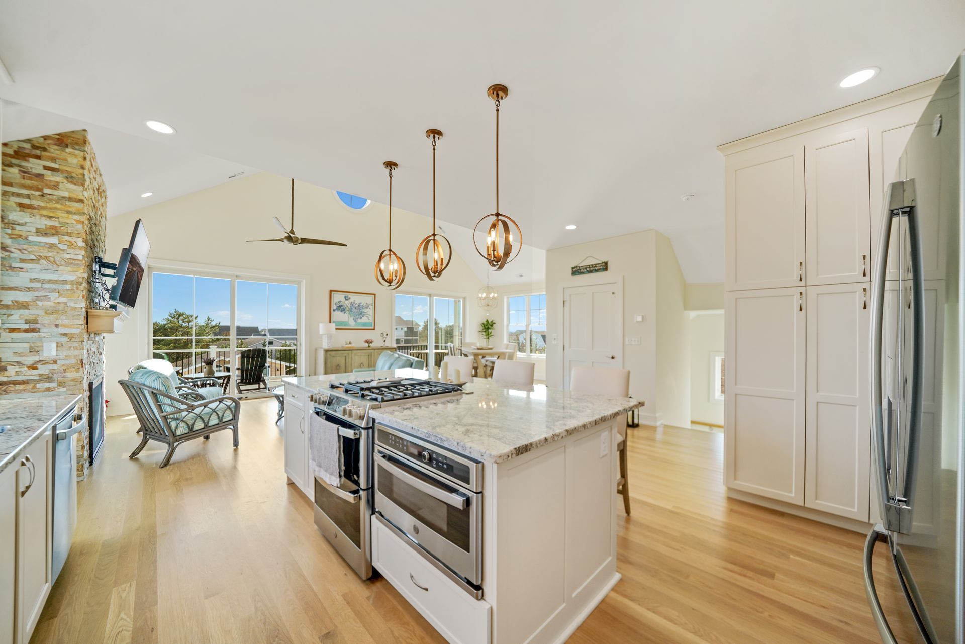 Bright modern kitchen with large island, pendant lights, and ocean view through wide windows