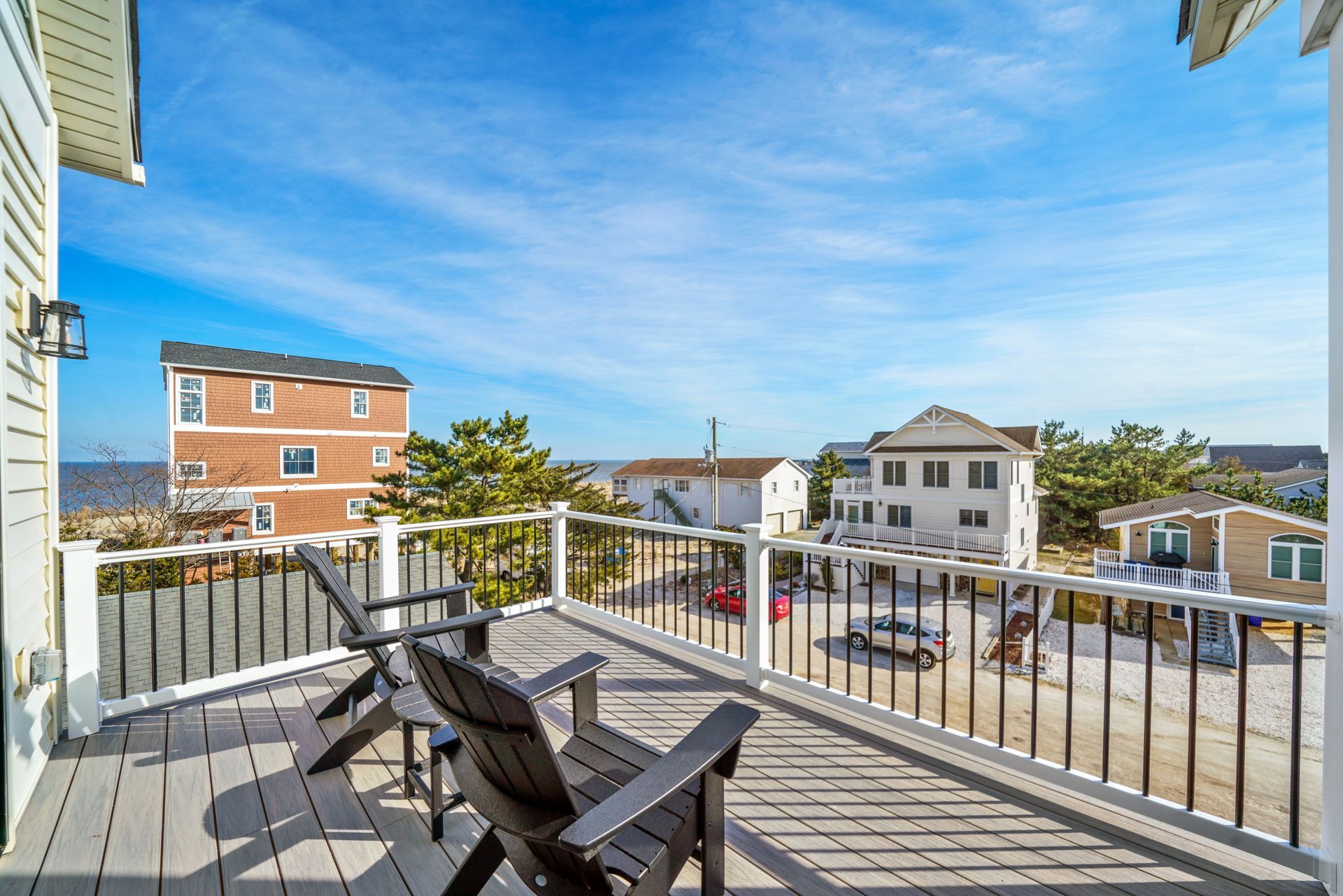 Balcony with chairs and a table overlooking neighboring houses under a blue sky