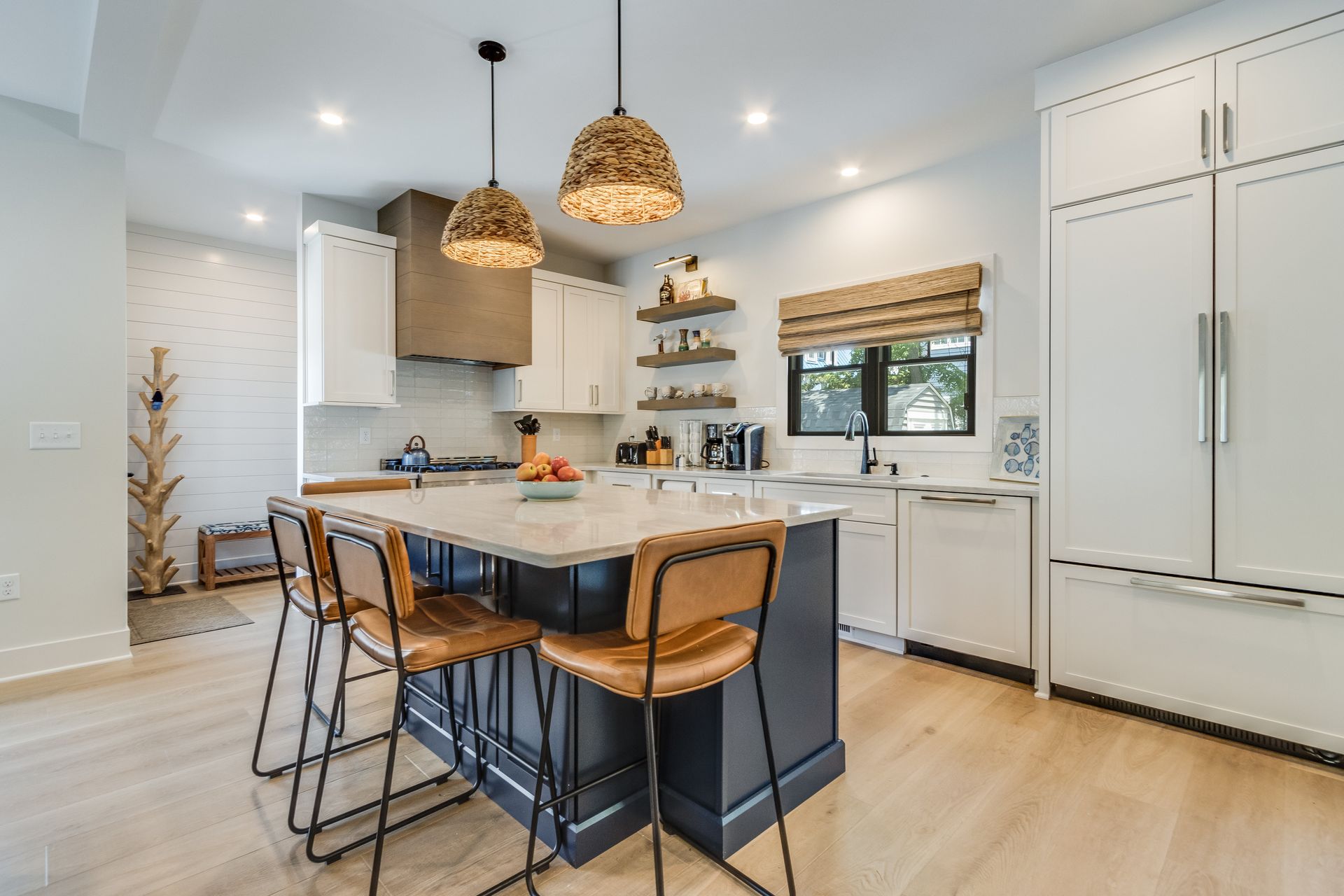 Modern kitchen with large island, white cabinets, and woven pendant lights.