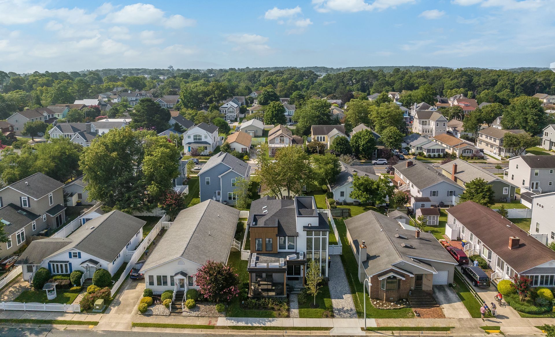 Aerial view of a residential neighborhood with houses, trees, and a blue sky.