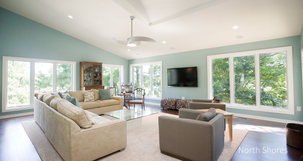 Spacious living room with blue walls, large windows, and neutral-colored furniture.