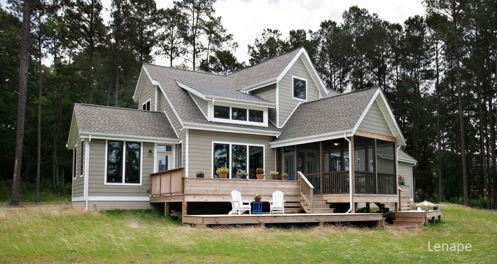 House with gray siding and a deck, surrounded by trees and grass.