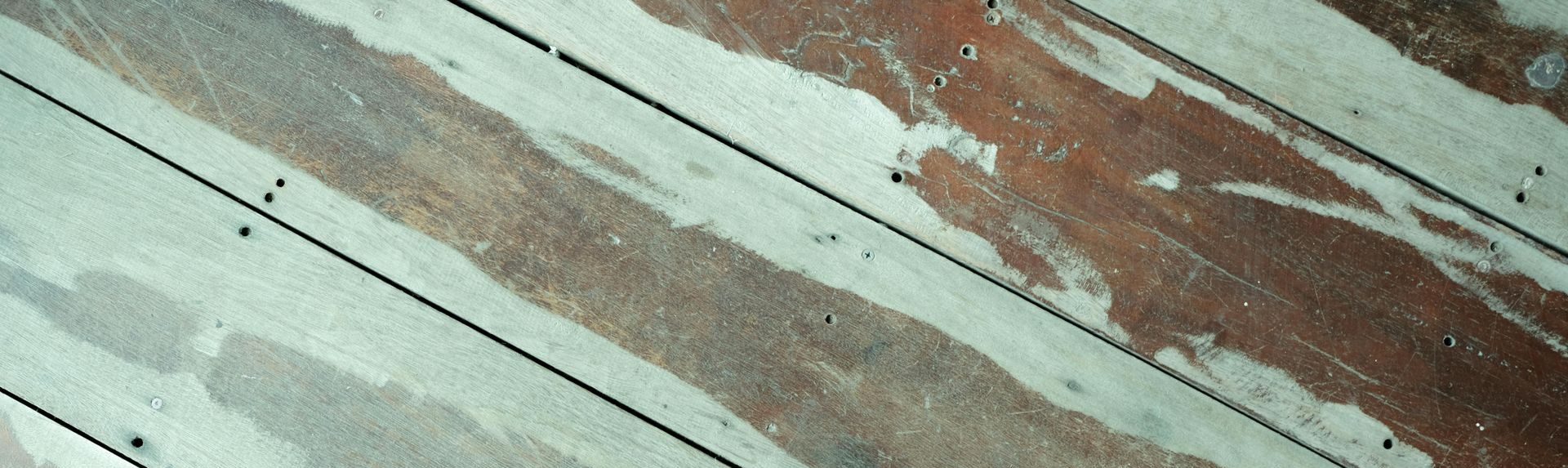 Diagonal weathered painted wooden planks in pale green, white, and reddish brown.