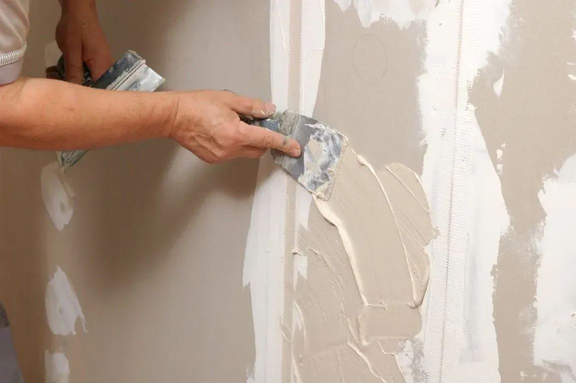 Professional taping and mudding drywall joints with a putty knife.