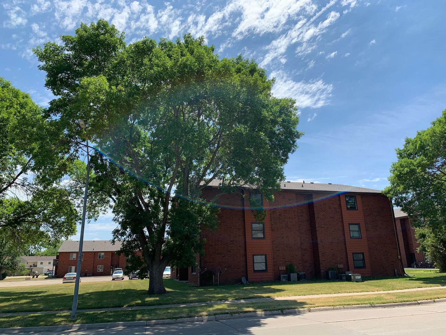 a large brick building with trees in front of it on a sunny day .