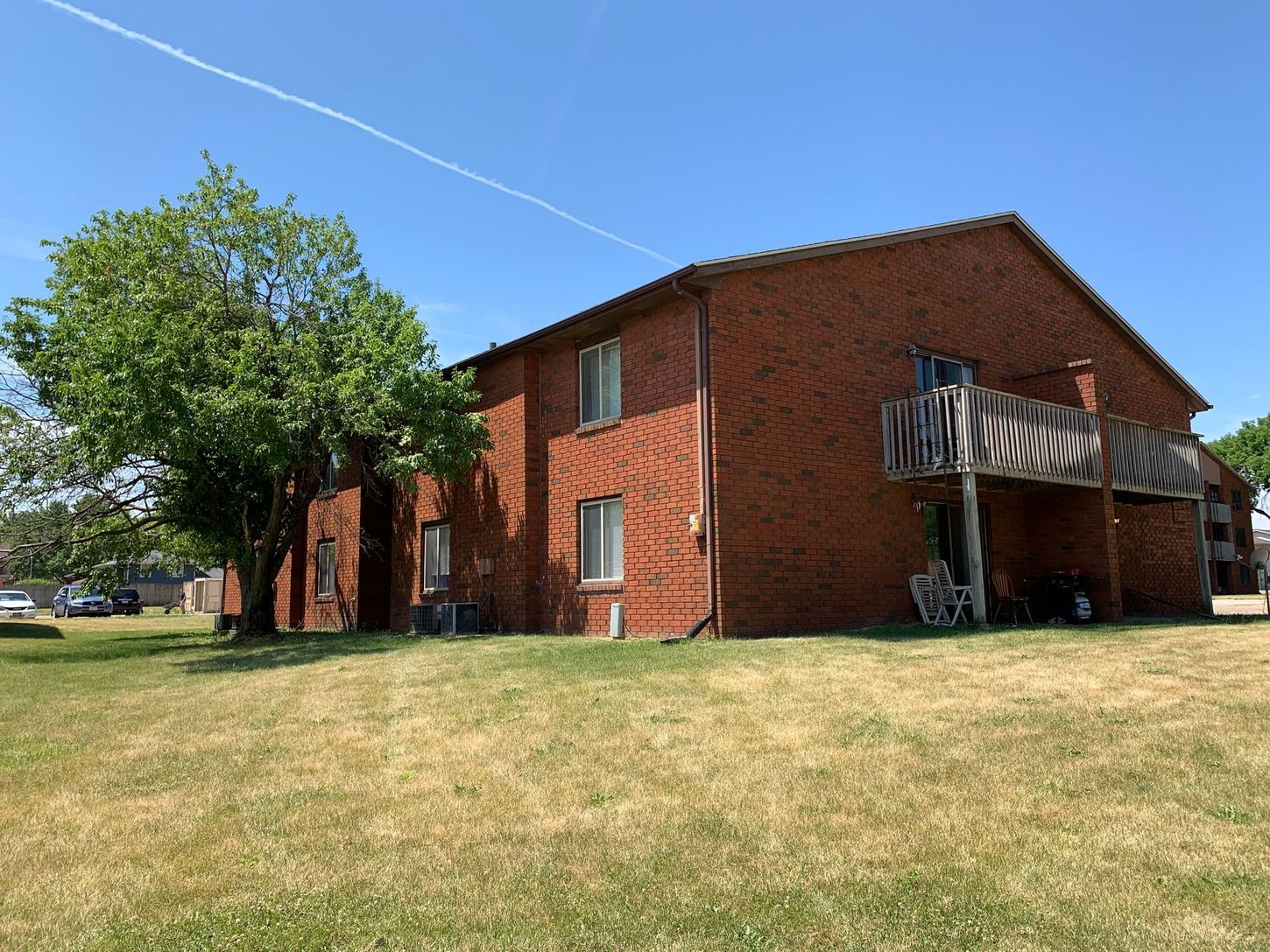 a brick apartment building with a balcony and a tree in front of it .