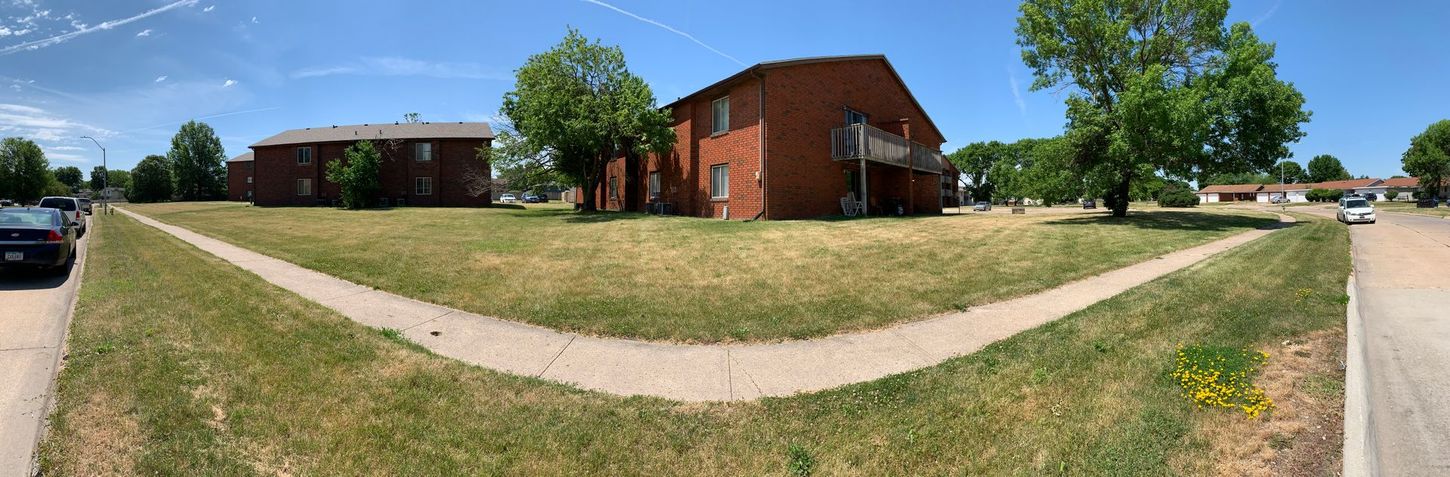 a panoramic view of a residential area with a brick building and a sidewalk .