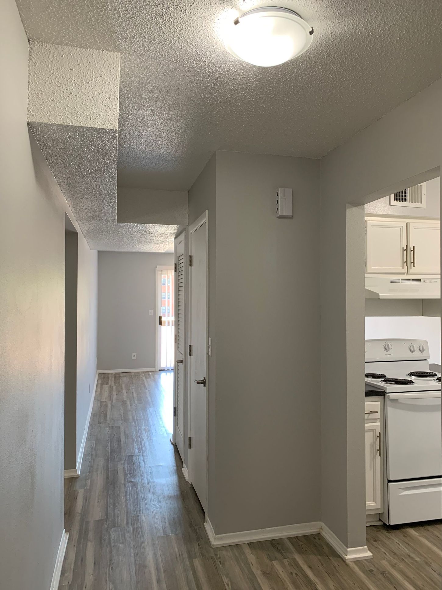 a long hallway leading to a kitchen in a house .