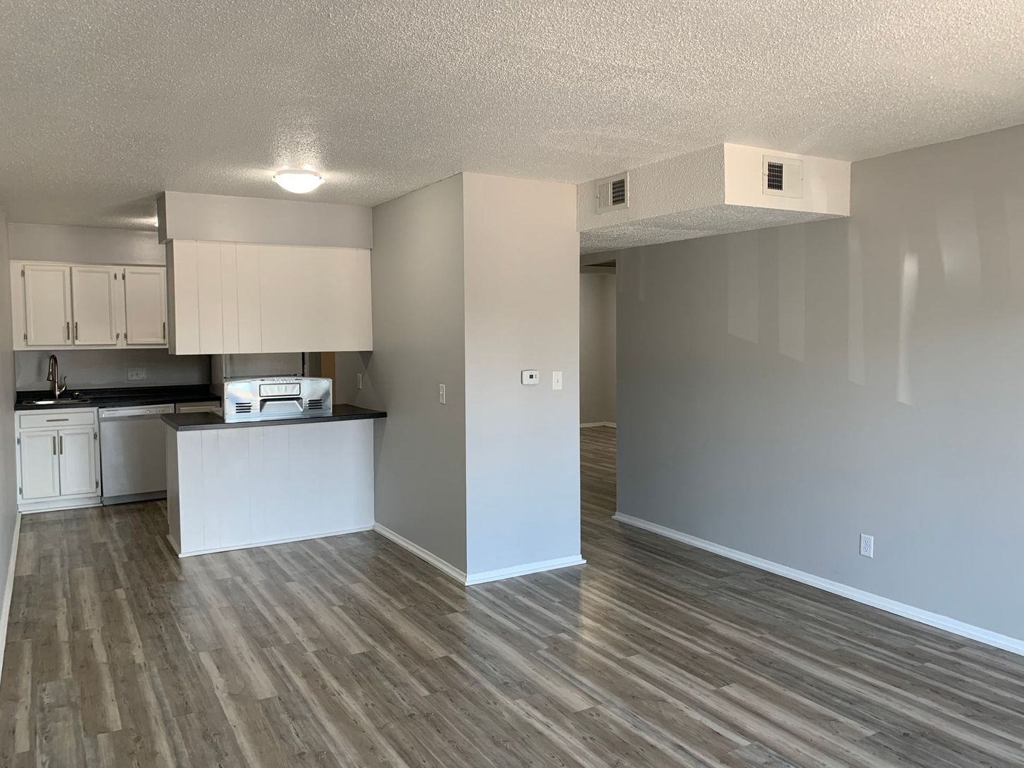 a living room with hardwood floors and a kitchen in the background .