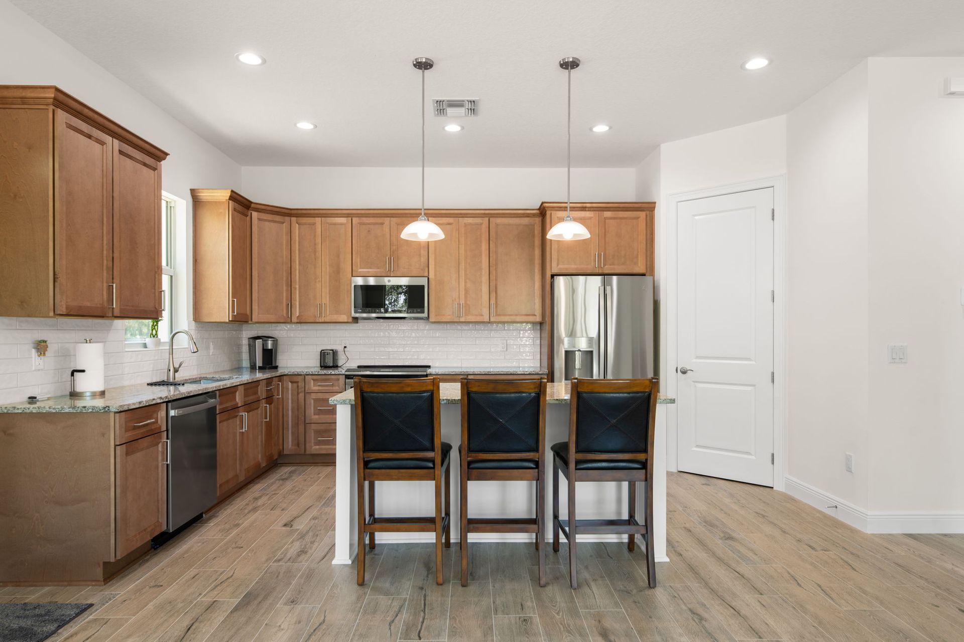 Kitchen with wooden cabinets, stainless steel appliances, and island with bar stools.