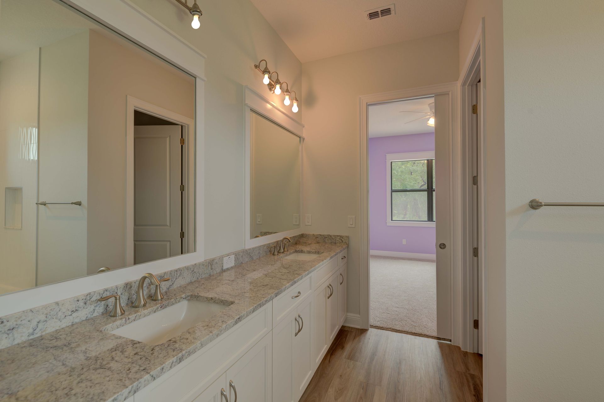 Open-concept kitchen and living area with black island, white cabinets, and large glass doors leading to a pool.