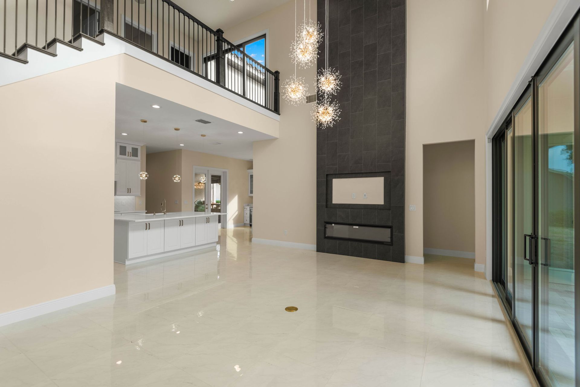 Spacious, modern living room with high ceilings, fireplace, and sliding glass doors.  Staircase and open loft area.