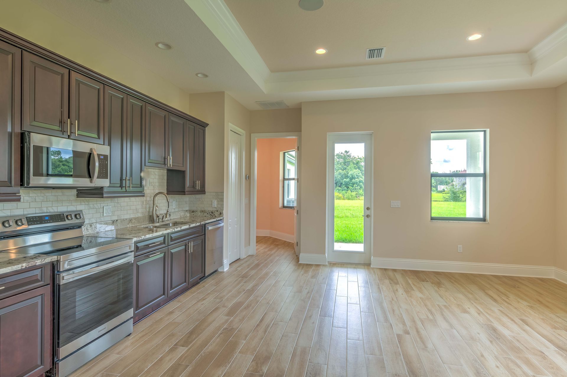 Kitchen with dark cabinets, stainless steel appliances, light wood floors, and neutral walls.