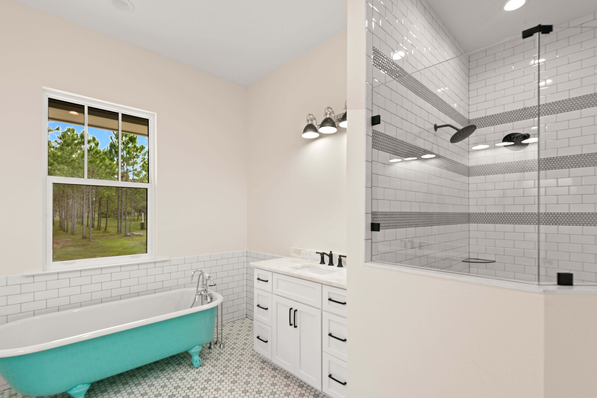 Bathroom with turquoise tub, white vanity, walk-in shower, and window overlooking trees.