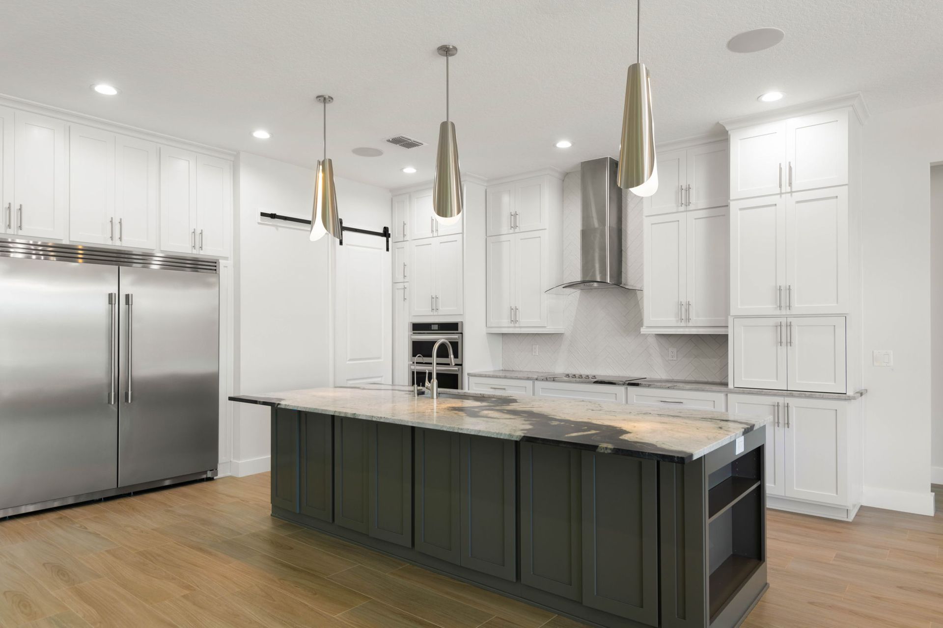 Modern white kitchen with a gray island, stainless steel appliances, and wood floors.