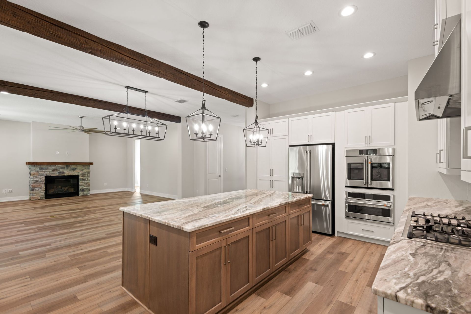 Spacious kitchen with wood cabinets, island, and stainless steel appliances. Fireplace and exposed beams.