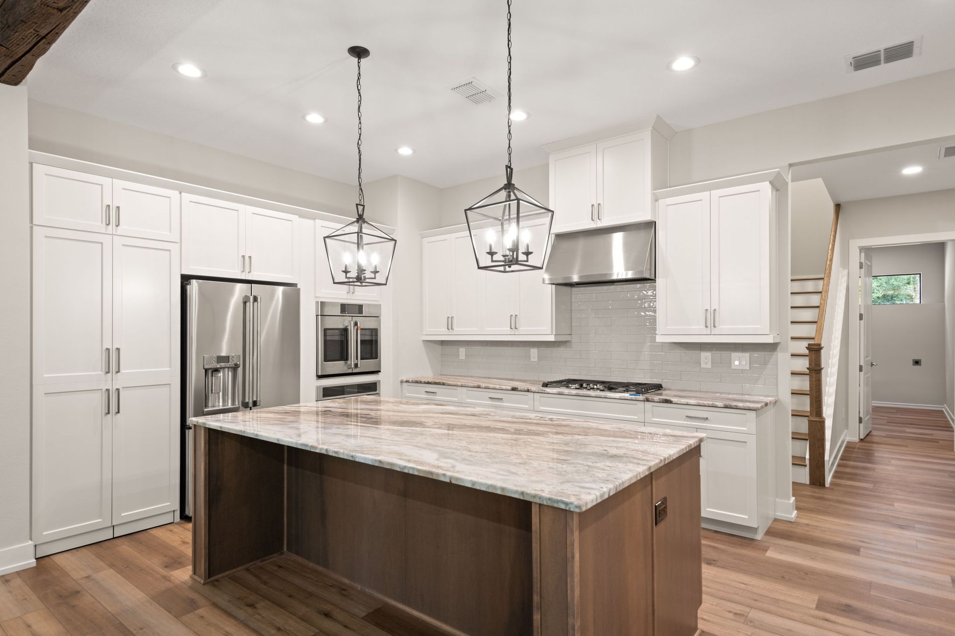 Modern kitchen with white cabinets, stainless steel appliances, and a large island.