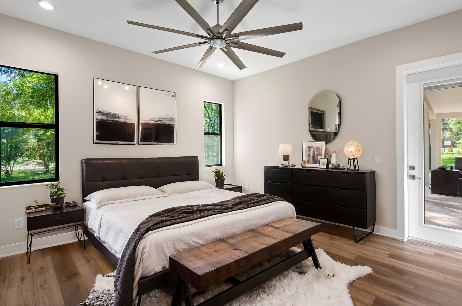 Bedroom with king-sized bed, black dresser, and large windows with outdoor views.