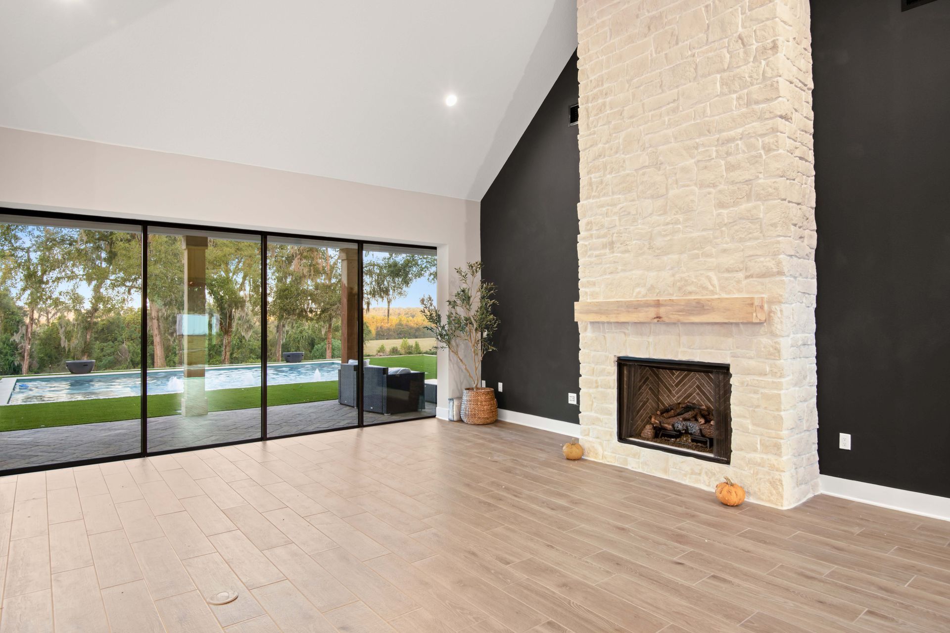 Empty living room with fireplace, sliding glass doors to a pool.