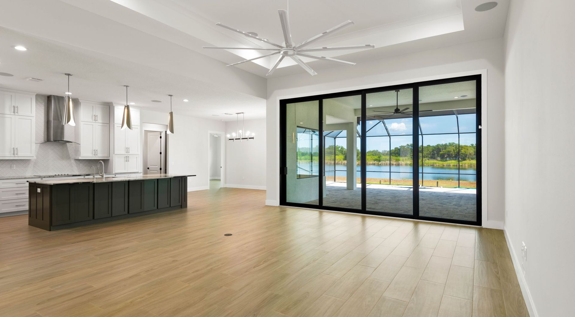 Spacious, modern interior with kitchen island and sliding glass doors to a lake view.