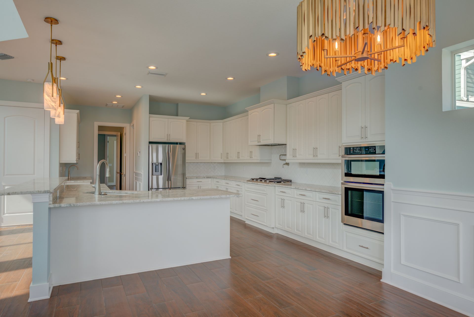 White kitchen with island, stainless steel appliances, and dark wood floors.