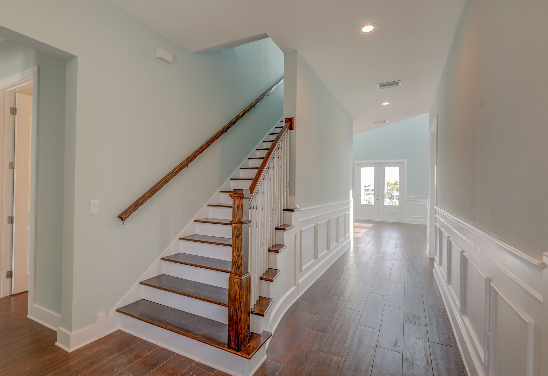 Interior hallway with wooden staircase and light blue walls.