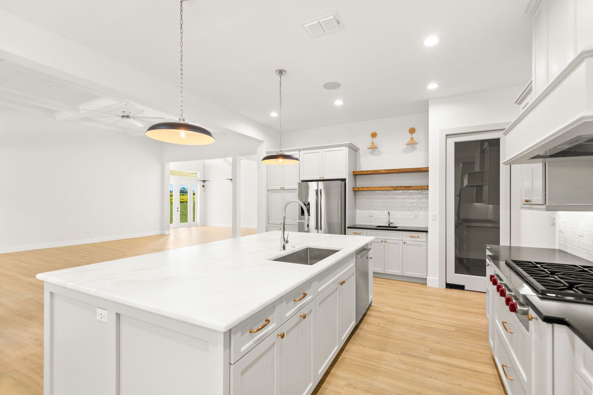 Bright, modern kitchen with a white island, stainless steel appliances, and wood flooring.