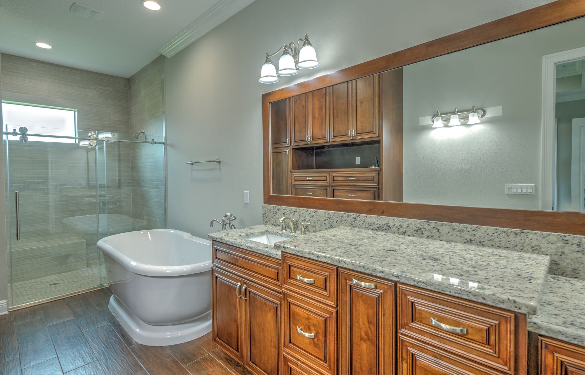 Bathroom with a freestanding tub, wood cabinets, and granite countertop.