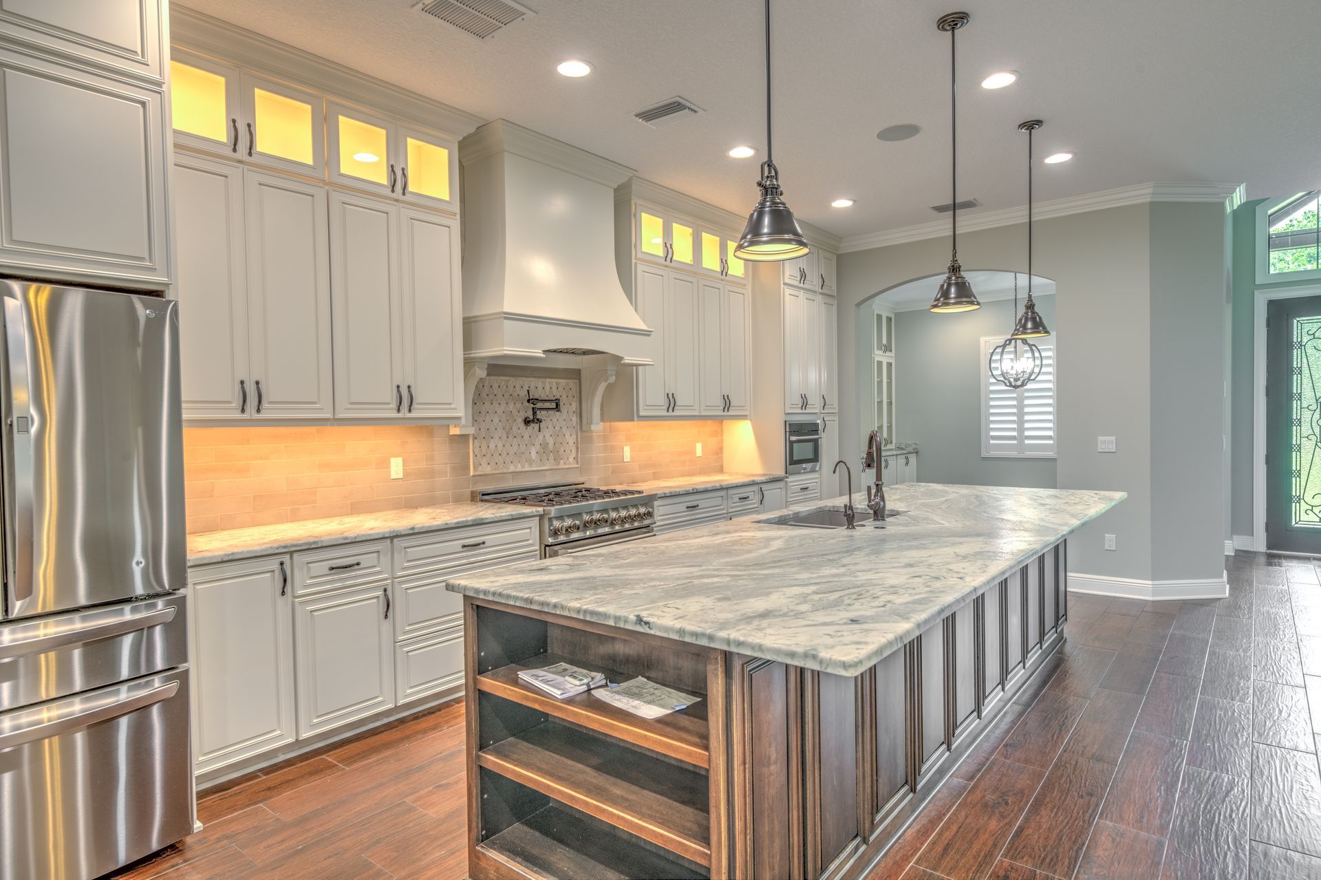 Upscale kitchen with a large island, stainless steel appliances, and wood floors.