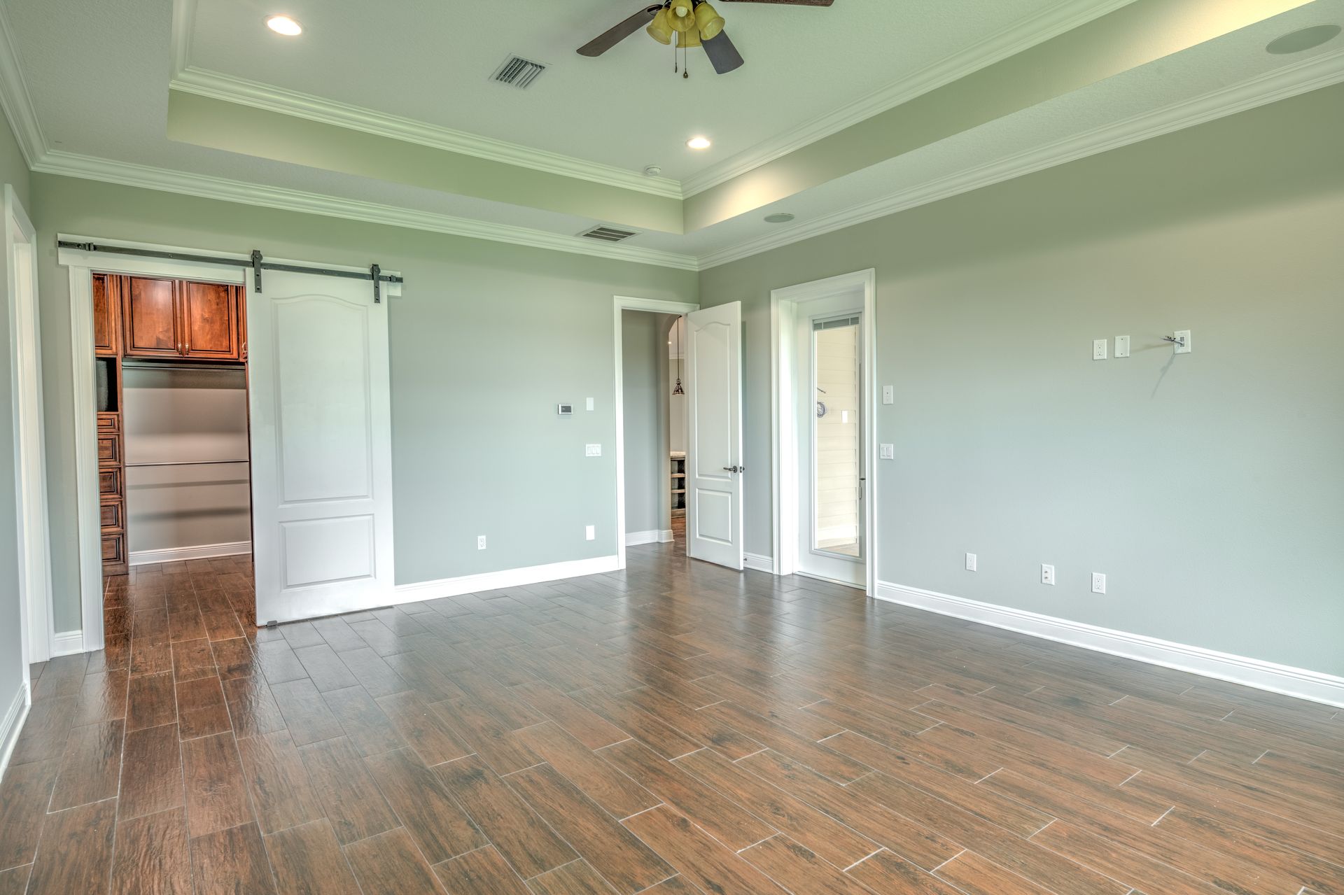 Empty bedroom with dark wood floor, light blue walls, white trim, and a ceiling fan.